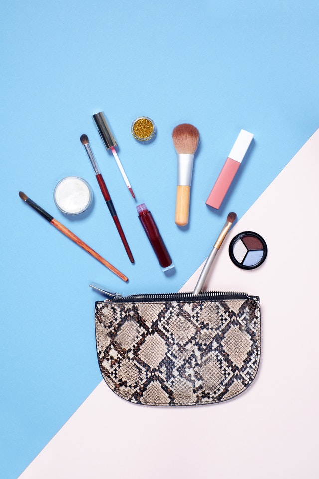 Make-up-Tasche aus Stoff, Pinsel und Kosmetikprodukte drumherum