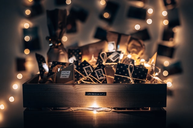 Eine Kiste mit selbstgemachtem Adventskalenderpäckchen, drumherum eine Lichterkette