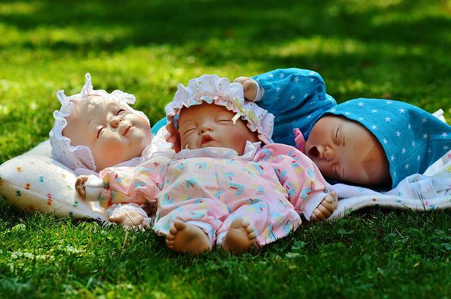 Drei Puppen liegen auf dem Gras
