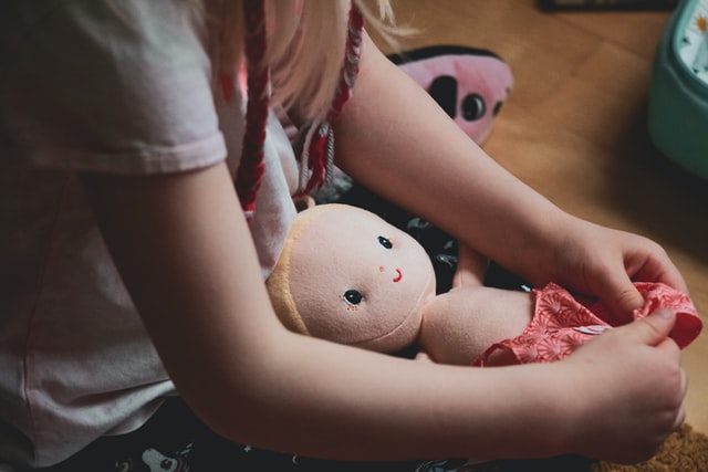 Kind zieht Puppe an