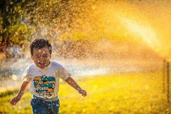 Ein Junge mit bedrucktem Shirt läuft durch herumspritzendes Wasser