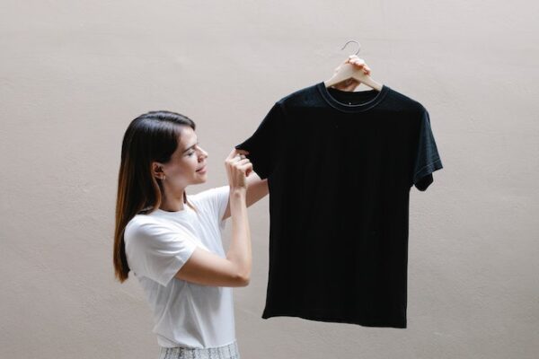 Frau hält ein schwarzes T-Shirt hoch