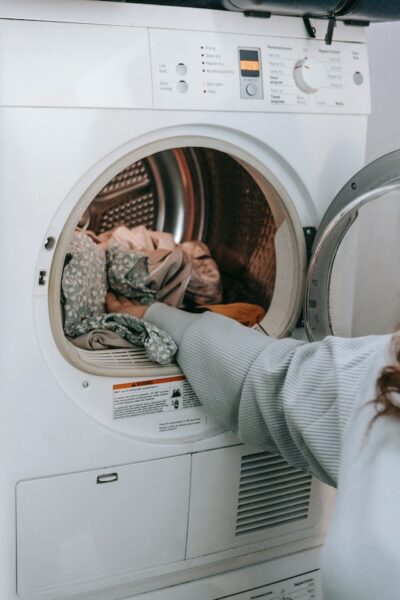 Person steckt Wäsche in die Waschmaschine
