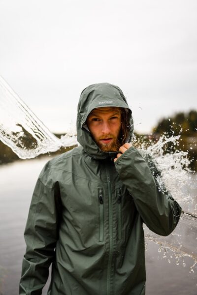Ein Mann in grüner Regenjacke wird mit Wasser bespritzt