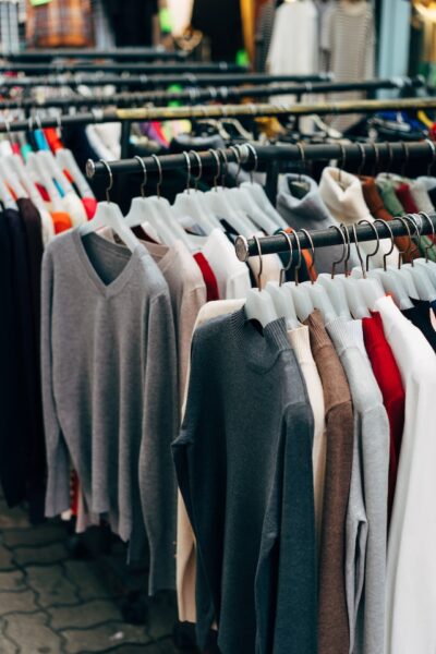 Viele unterschiedliche Pullover hängen auf mehreren Kleiderstangen hintereinander