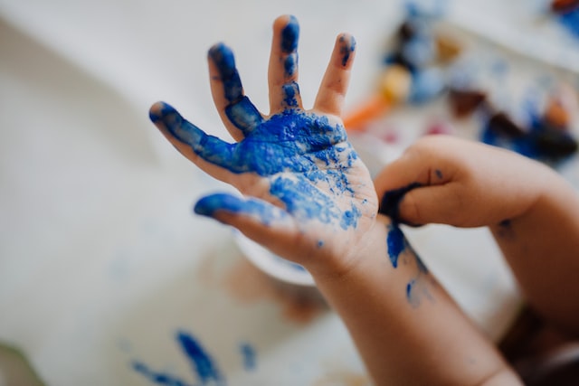 Eine Kinderhand voller blauer Farbe