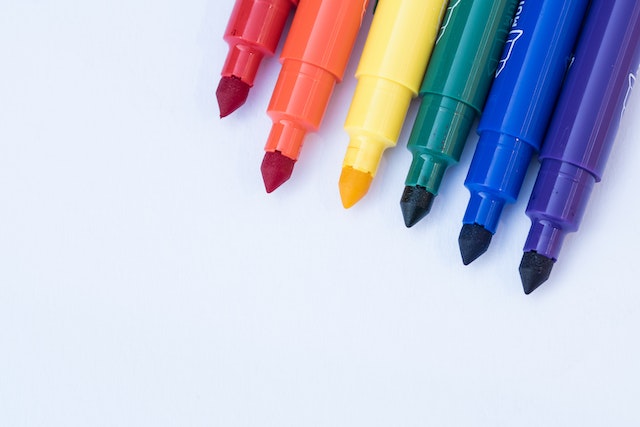 Stifte in Regenbogenfarben liegen aufgereiht nebeneinander
