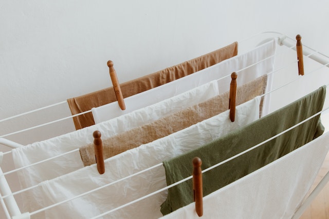 Auf einem Wäscheständer hängen mehrere frisch gewaschene Textilien in neutralen Farben 