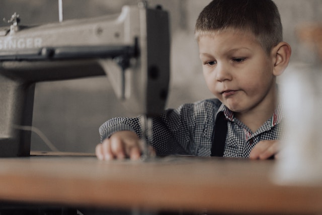 Ein Junge arbeitet an einer Nähmaschine und schaut sehr konzentriert