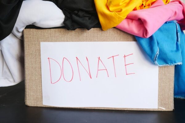 Ein Papkarton mit Aufschrift "Donate" voller zu spendender Kleidungsstücke