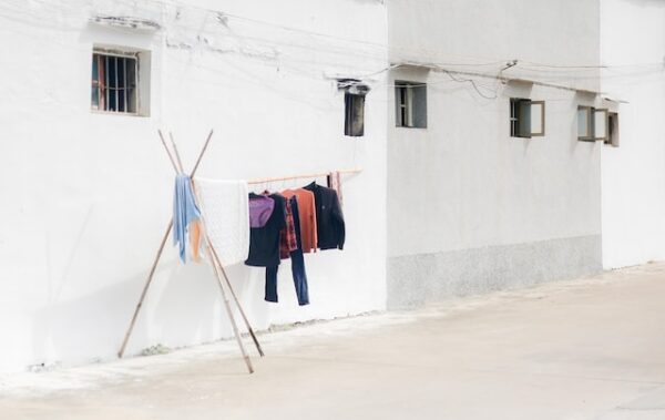 Kleidung hängt vor einer Hauswand auf einer Wäscheleine